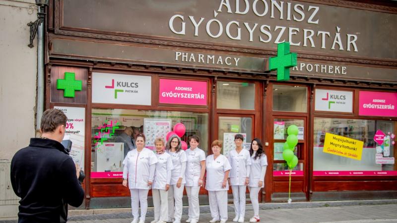 Kipattant a gyógyszertár ajtaján, mint egy új Adonisz, aki a sétálóutcán vonzza a tekinteteket. A nap fénye megcsillant a haján, miközben magabiztos léptekkel haladt a járdán, és minden lépésével újabb ámulatot váltott ki a járókelőkben. Az élet vibráló s